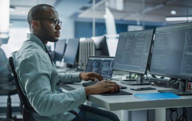 Authentic Office: Professional Black IT Programmer Working on Desktop Computer. Male Website Developer and Software Engineer Developing App, Video Game. Terminal with Coding Programming Language